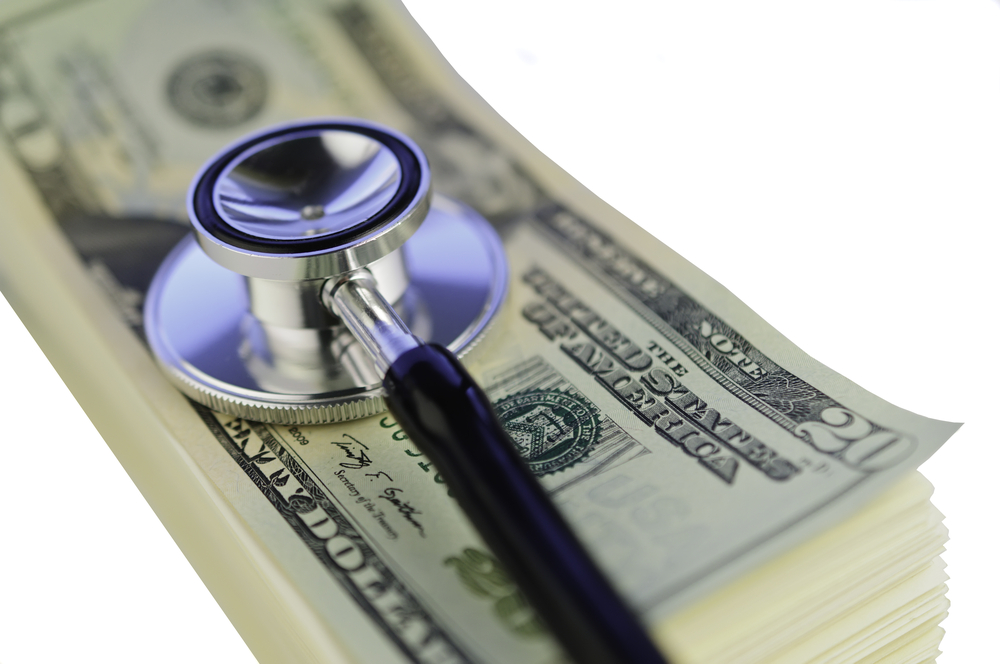 Stethoscope on stack of U.S. dollar bills representing healthcare costs and insurance expenses